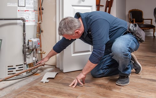 Inspector examining a floor for moisture near a water heater