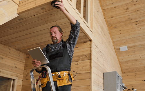 Inspector checking an interior ceiling with a flashlight and clipboard