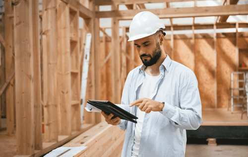 Home inspector reviewing plans inside a wood-framed building