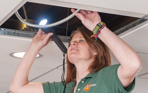 Inspector examining piping above a suspended ceiling