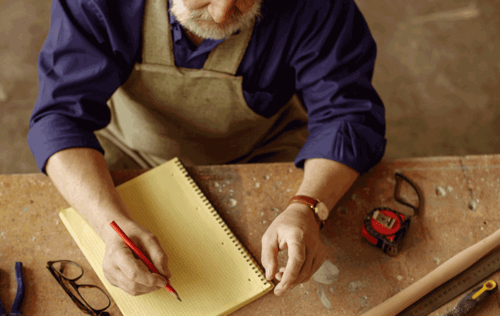 Carpenter making notes while working on wood
