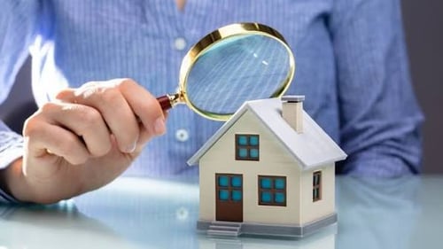 Image of person holding magnifying glass inspecting home